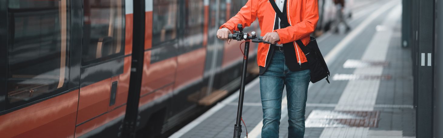 Електросамокат у поїзді Чоловік з електросамокатом біля поїзда